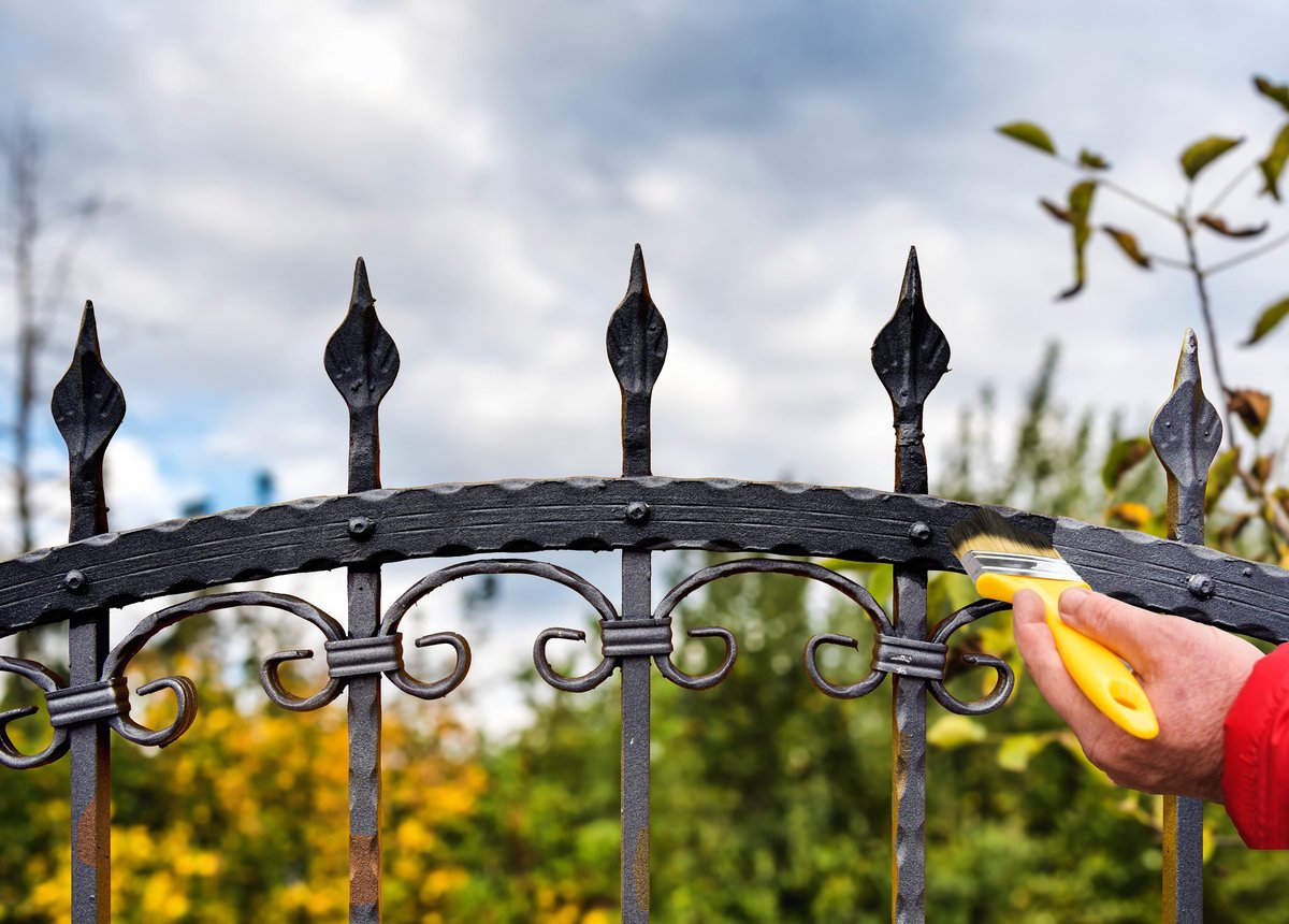 hand with brush painting wrought iron fence